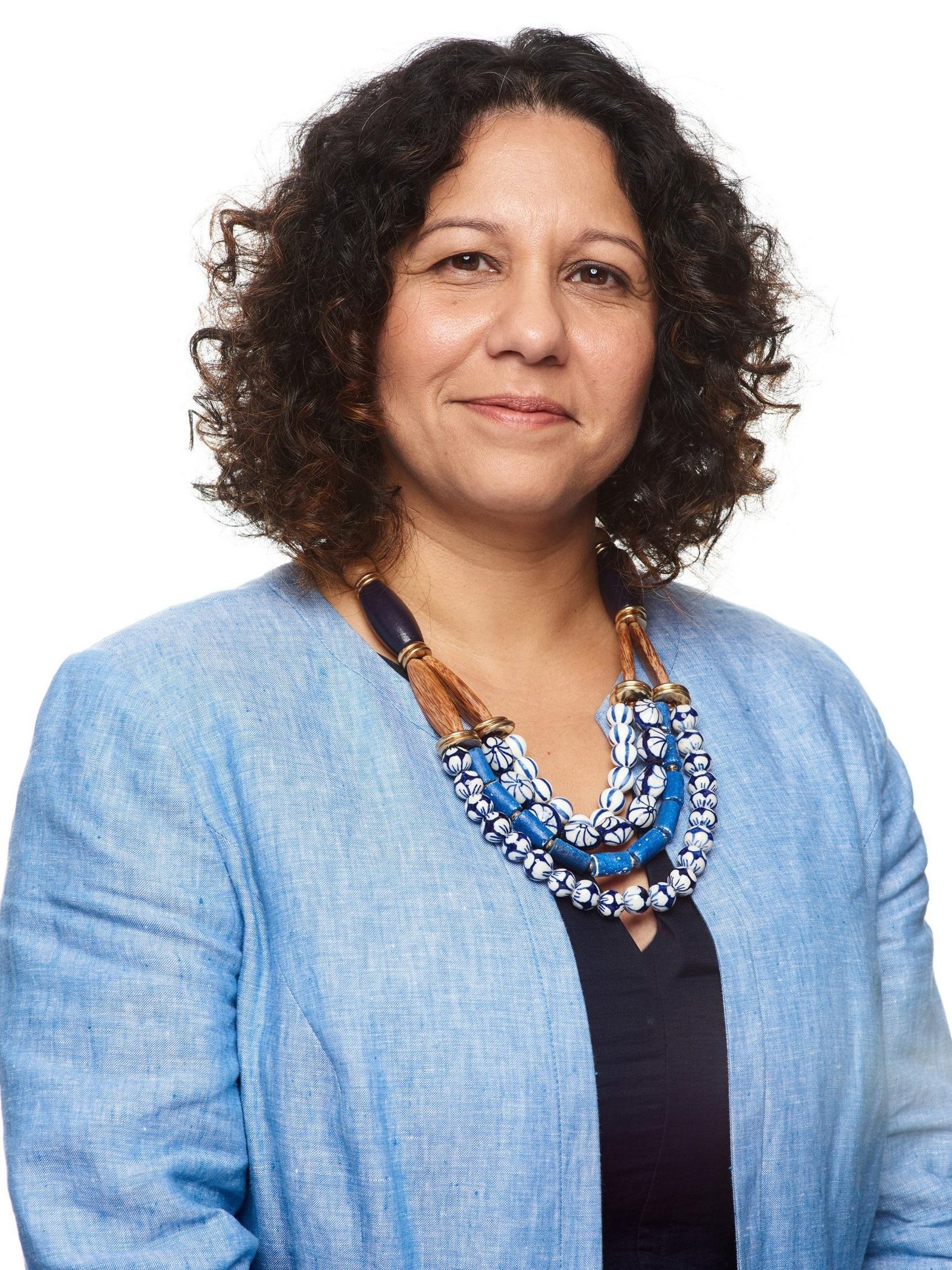 Studio corporate headshot of a woman with curly dark hair in a blue blazer on white