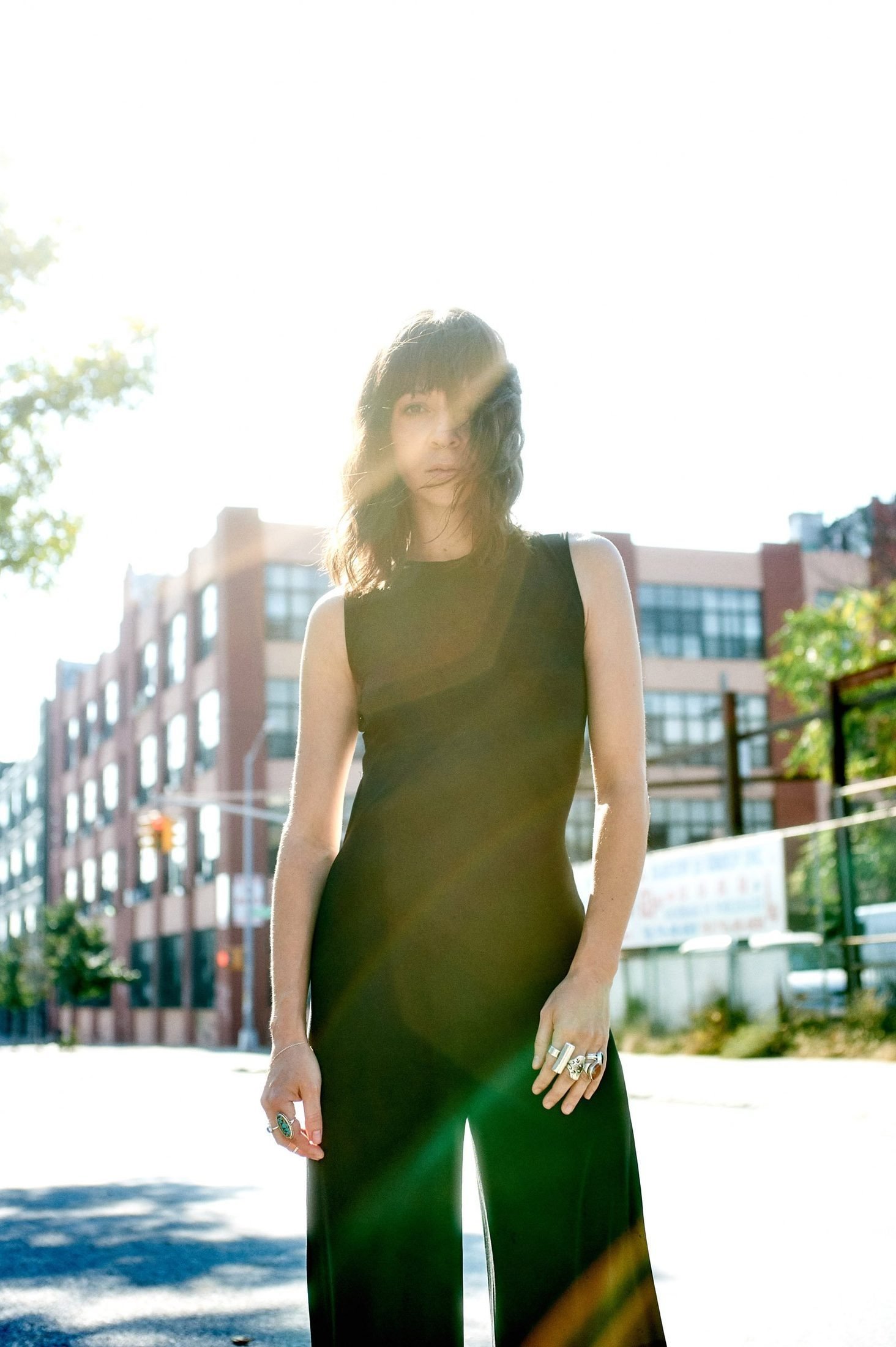 Outdoor branding portrait of a woman in a black jumpsuit backlit by afternoon sun