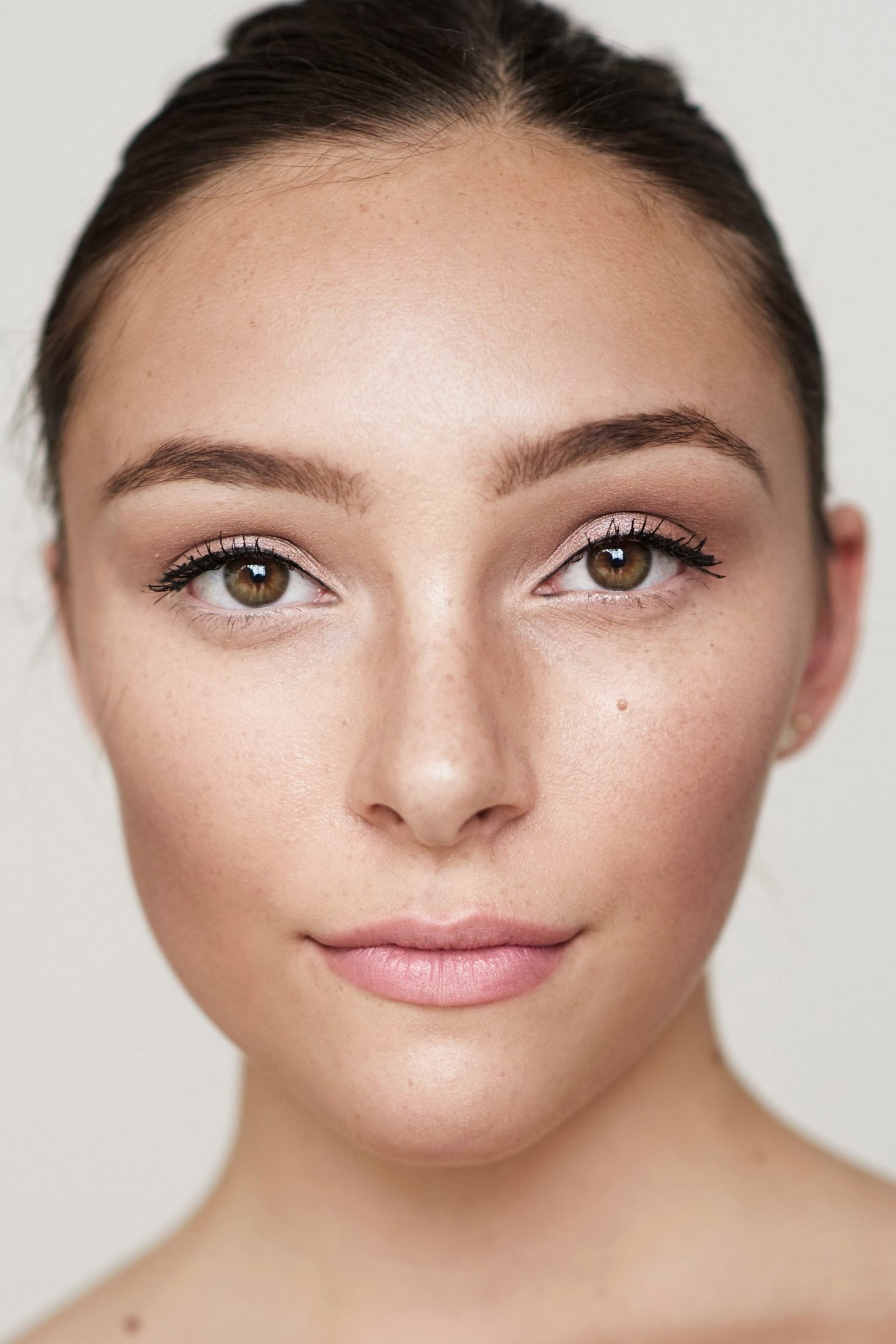 Close-up beauty portrait of a woman with minimal makeup looking directly at camera