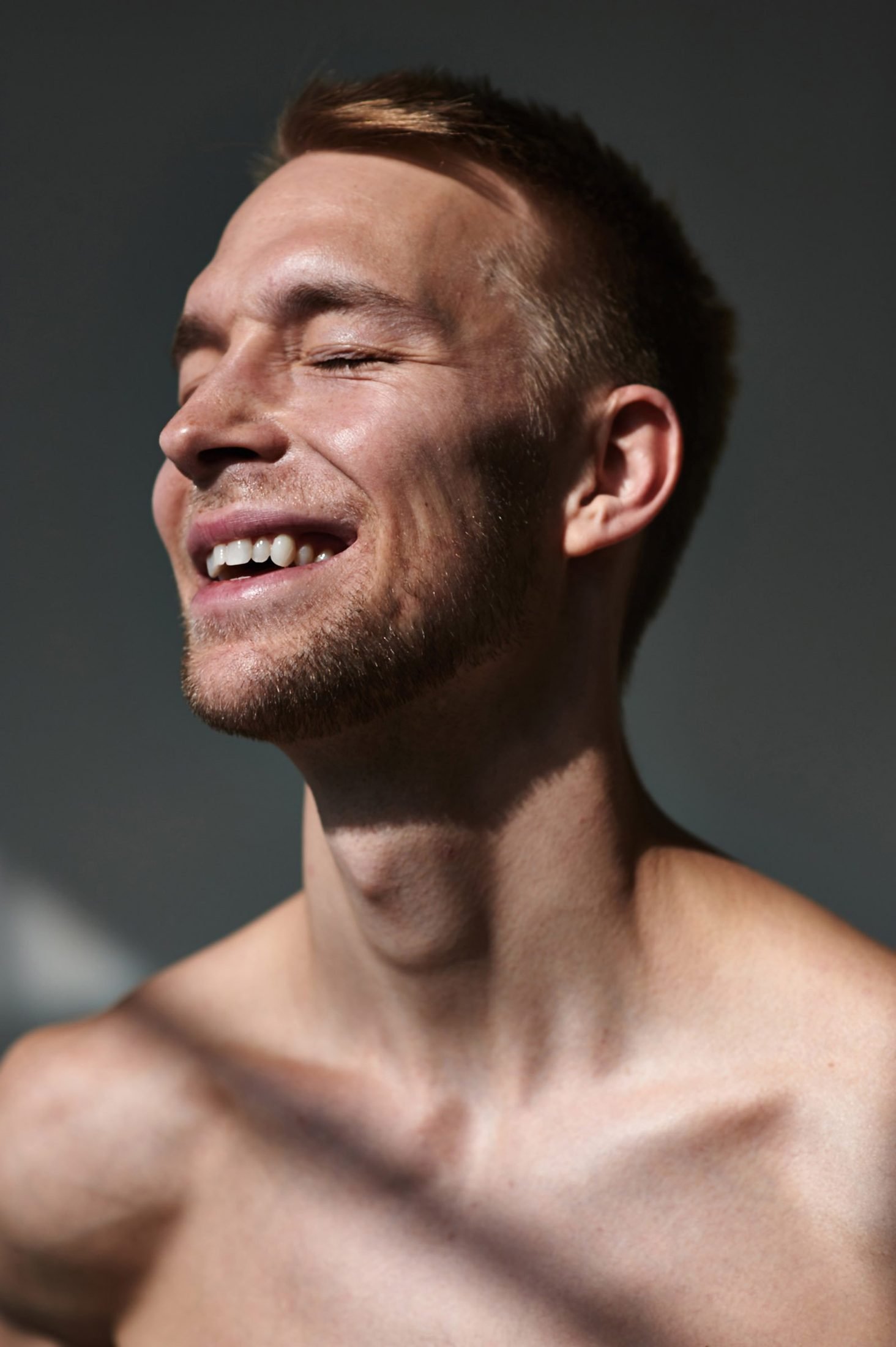 Dramatic low-key portrait of a bearded man laughing against a dark background