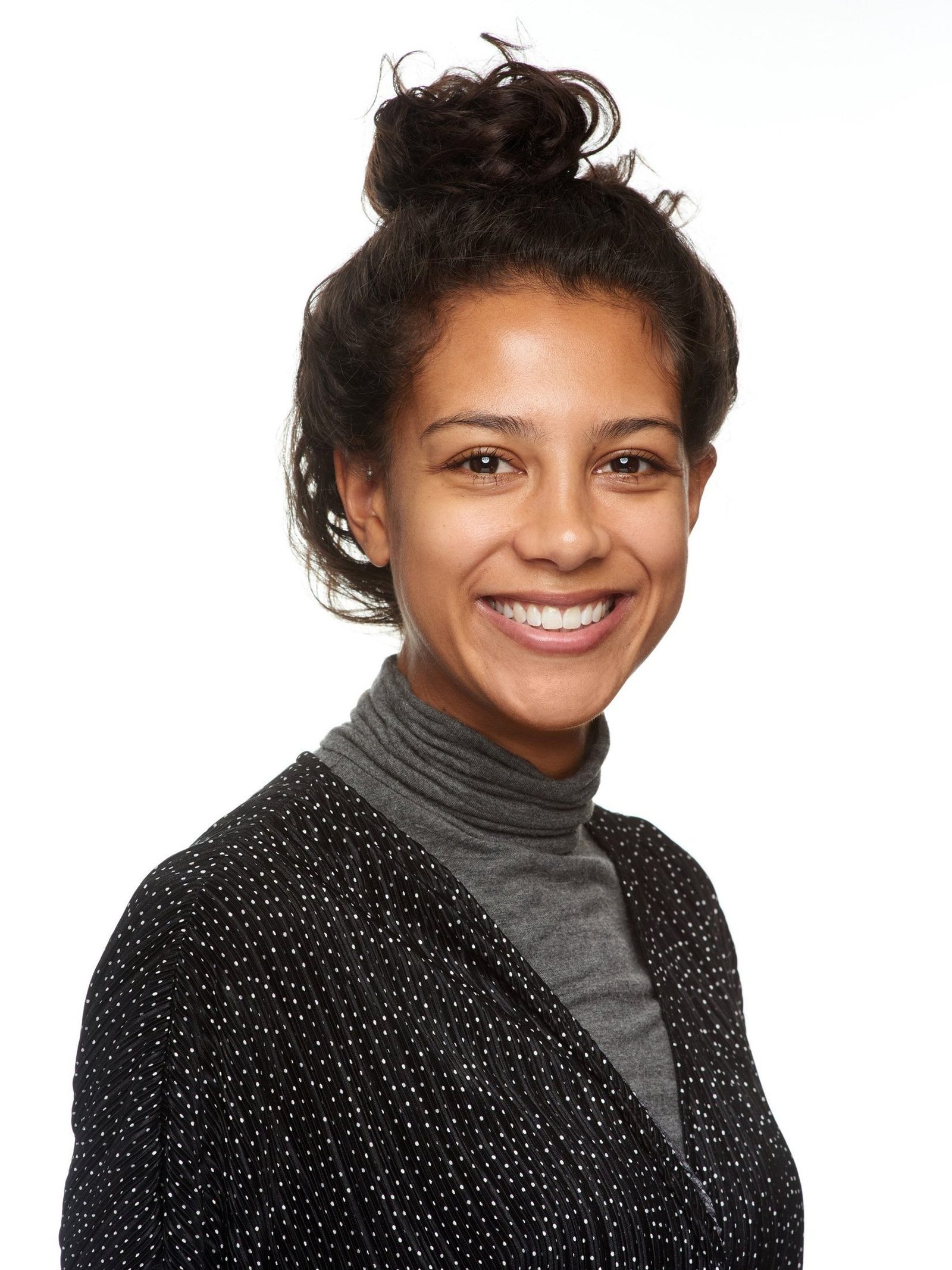 Business headshot of a young woman in a polka-dotted blazer and grey turtleneck
