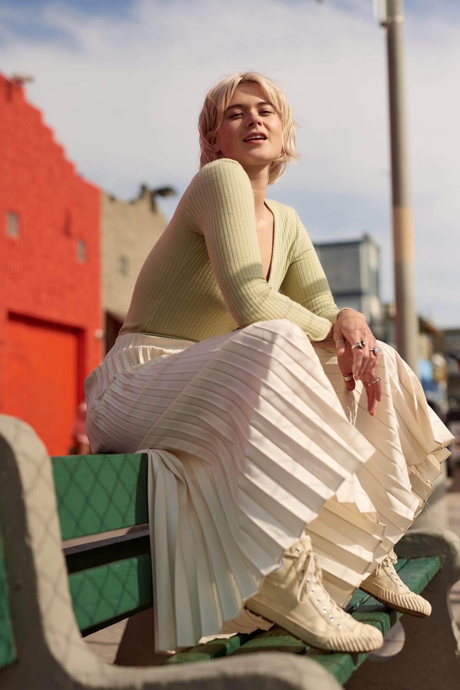Lifestyle branding portrait of a woman seated on a green park bench with a cityscape behind
