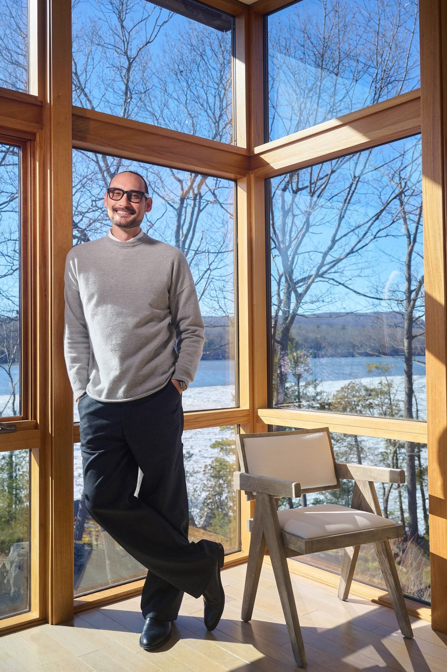 Environmental executive portrait of a man beside large windows overlooking a snowy lake