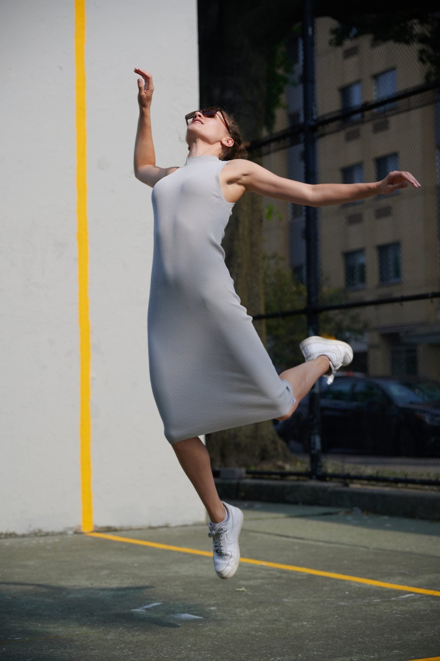 Motion portrait of a woman in a grey dress jumping on a sports court