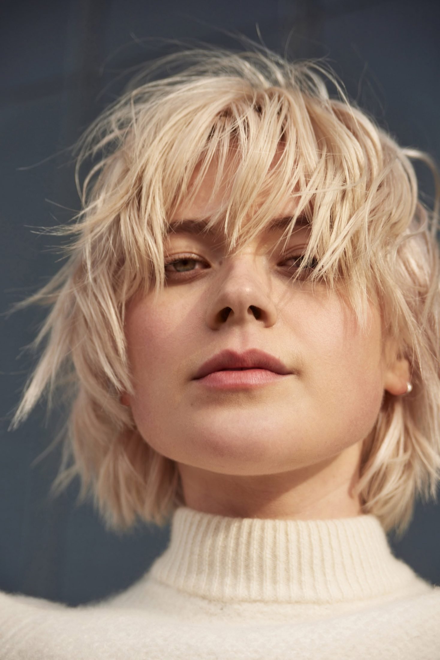 Moody portrait of a woman in a white turtleneck with hair across her face