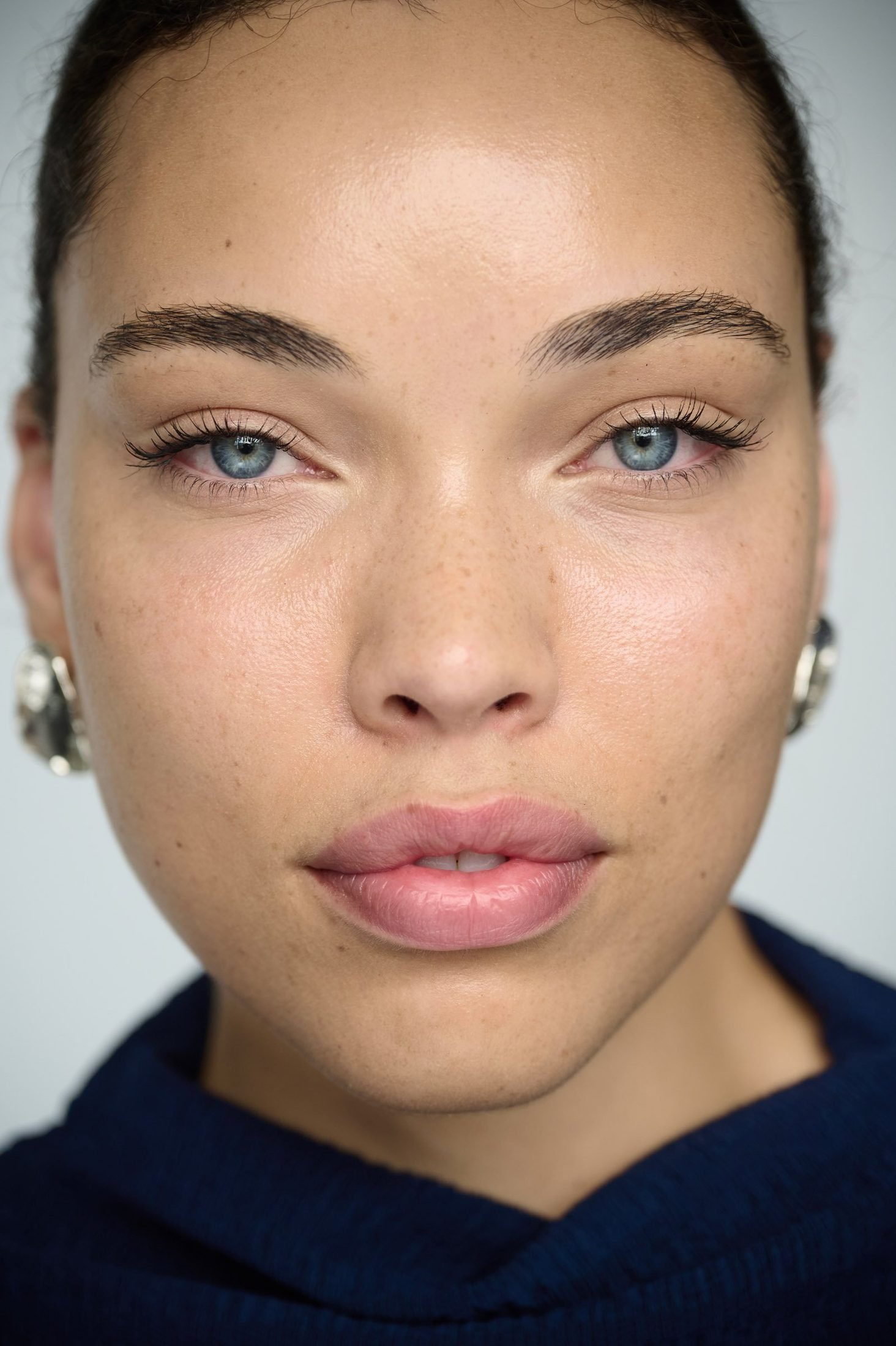Close-up portrait of a blue-eyed woman with light makeup and a dark top