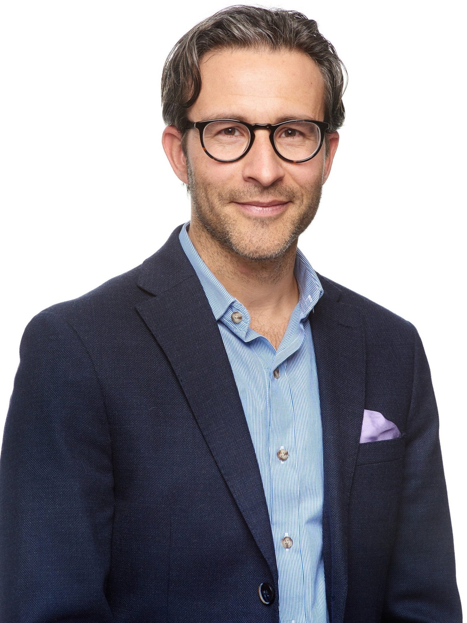 Business headshot of a bearded man in a dark blazer and striped shirt on white