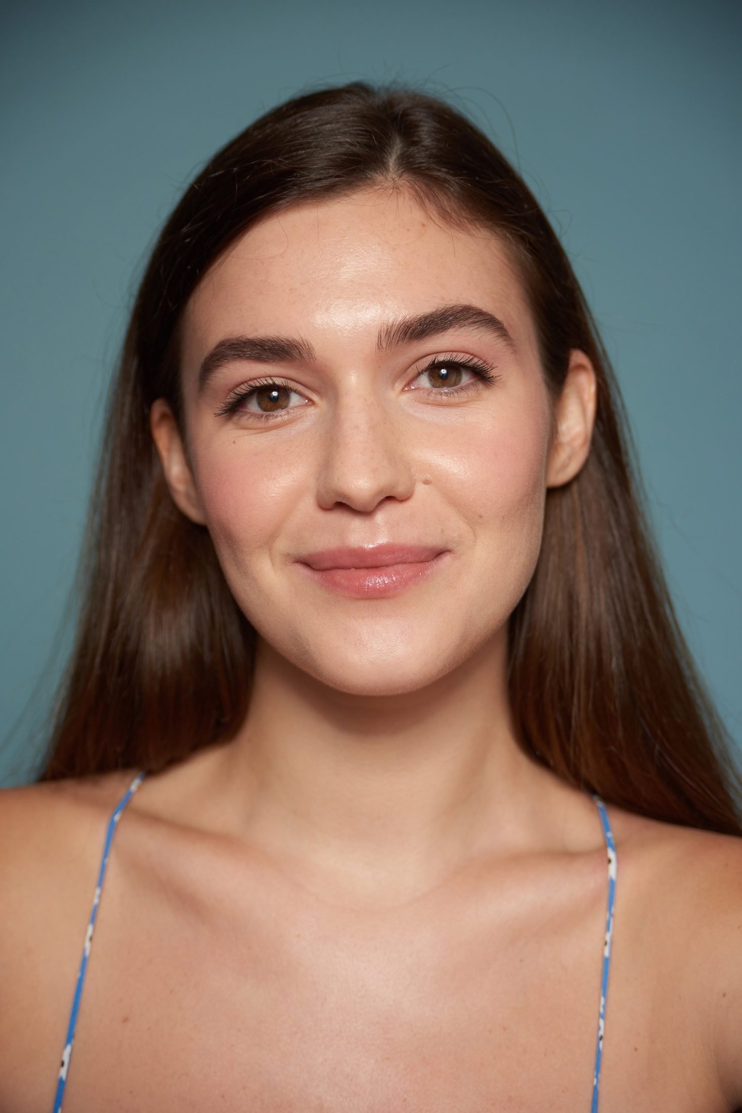 Soft portrait of a smiling young woman against a blue background
