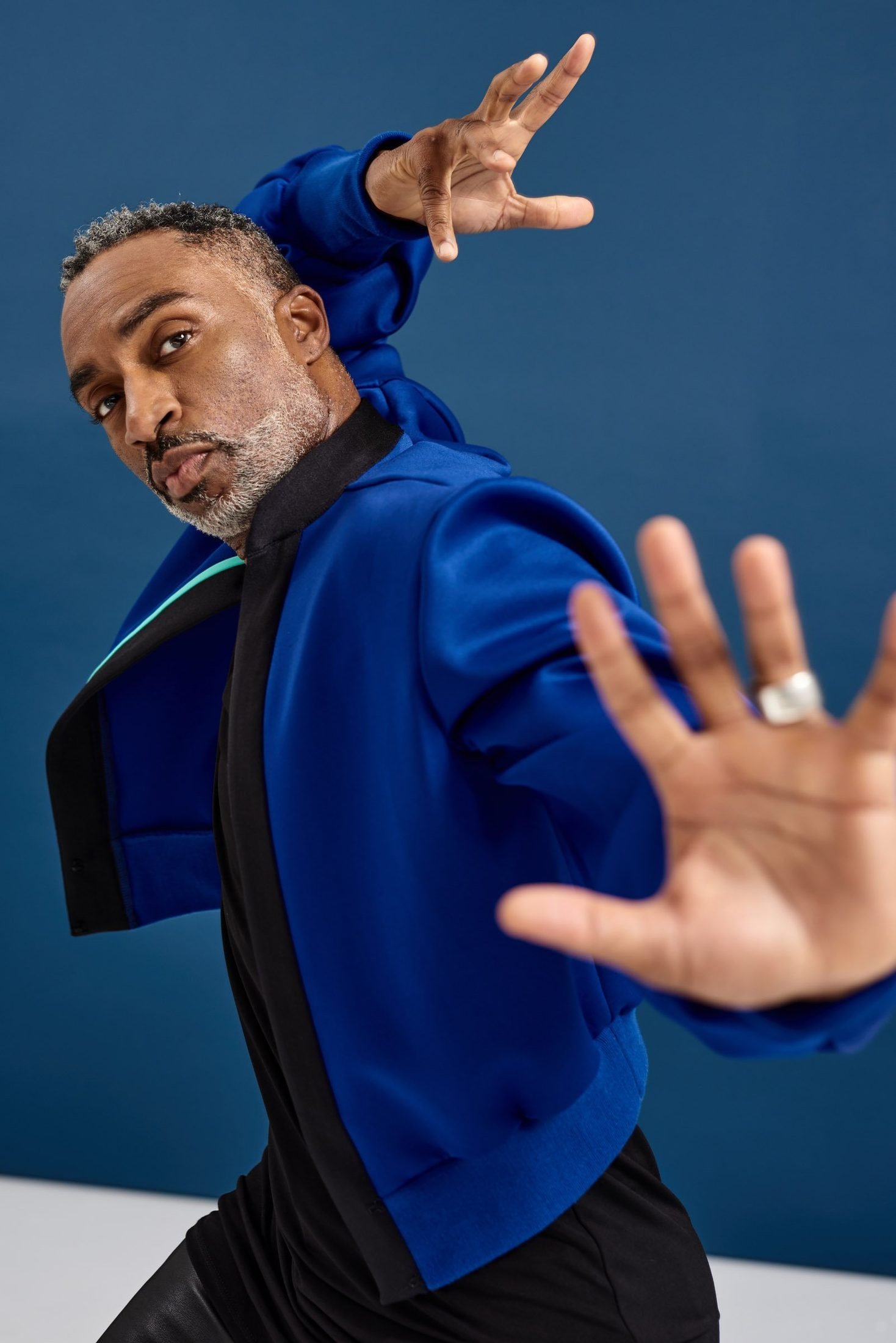 Movement portrait of a man in a blue jacket against a blue backdrop