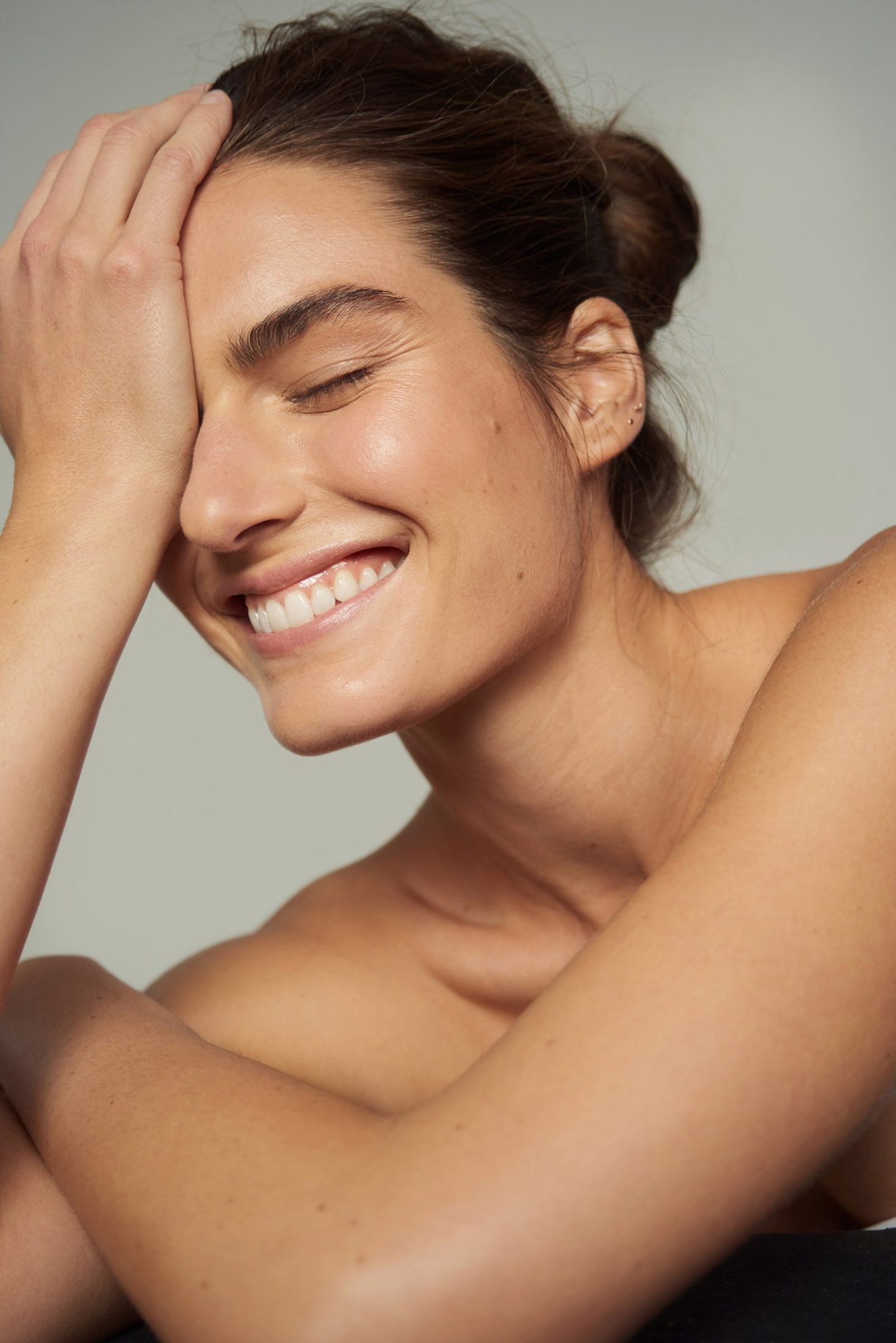 Beauty portrait of a smiling woman with her hand raised to her forehead