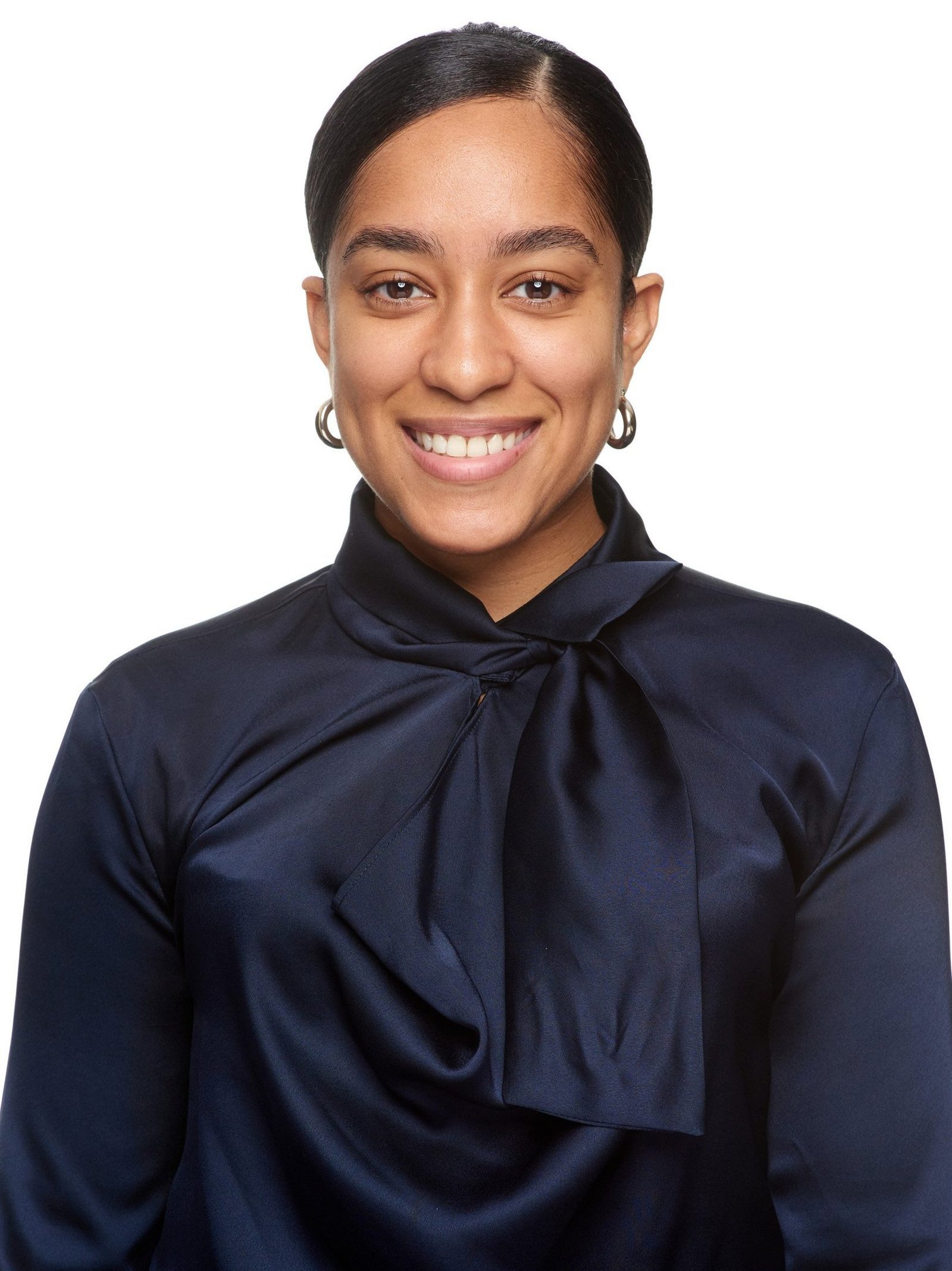 Corporate headshot of a woman in a navy blouse with a bow collar on white